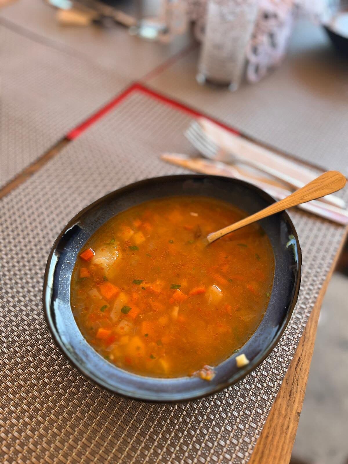 Bol cu supă de legume pe o masă de sub foișor