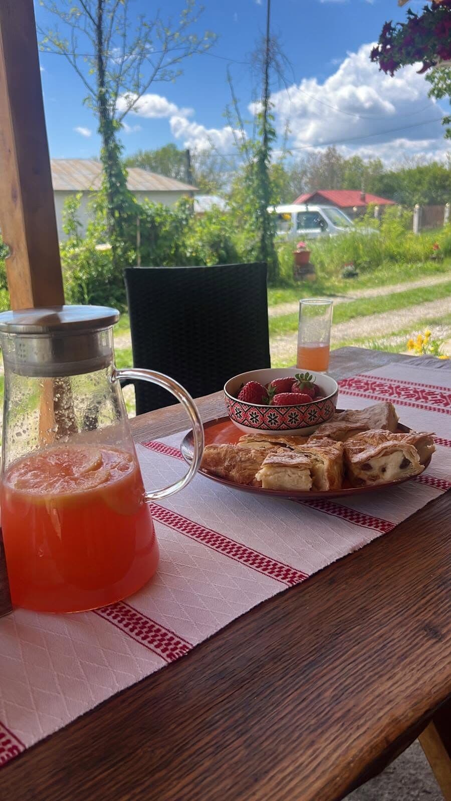 Carafă de limonadă și o farfurie cu prăjituri pe o masă cu față de masă tradițională
